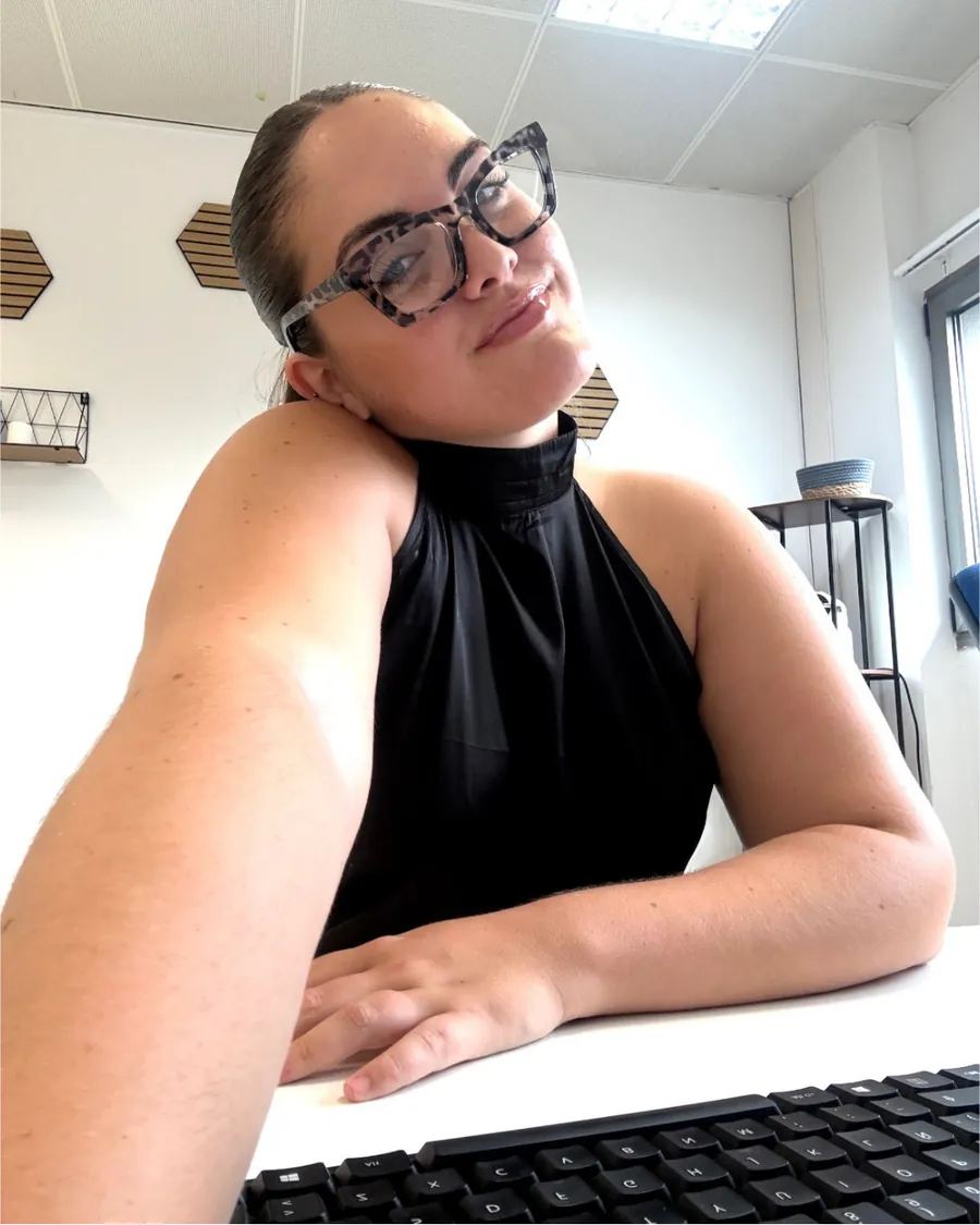 Ángela Bayo con gafas, apoyada en su escritorio y sonriendo